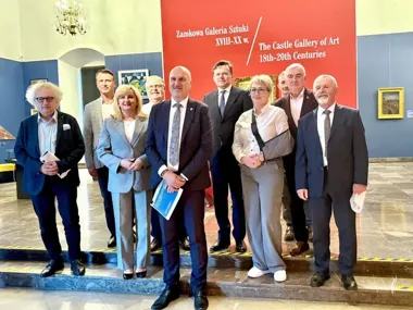 Grupa osób pozuje do pamiątkowego zdjęcia w holu Zamkowej Galerii Sztuki XVIII-XX w.